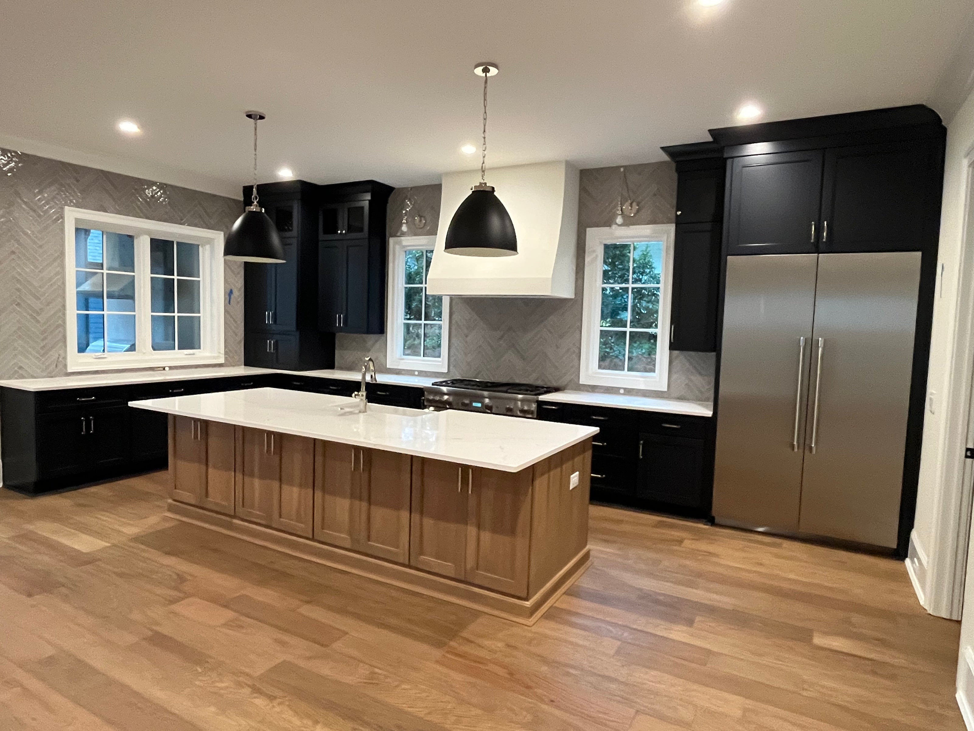 Finished kitchen with black cabinets, a wood island, and stainless steel appliances